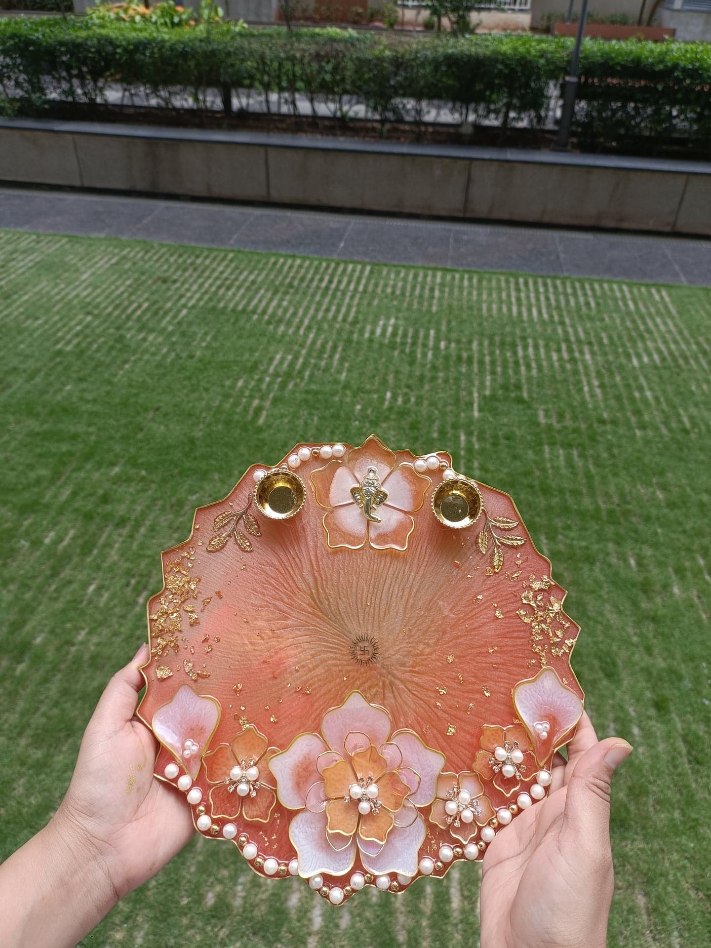 Peach floral resin pooja thali held outdoors