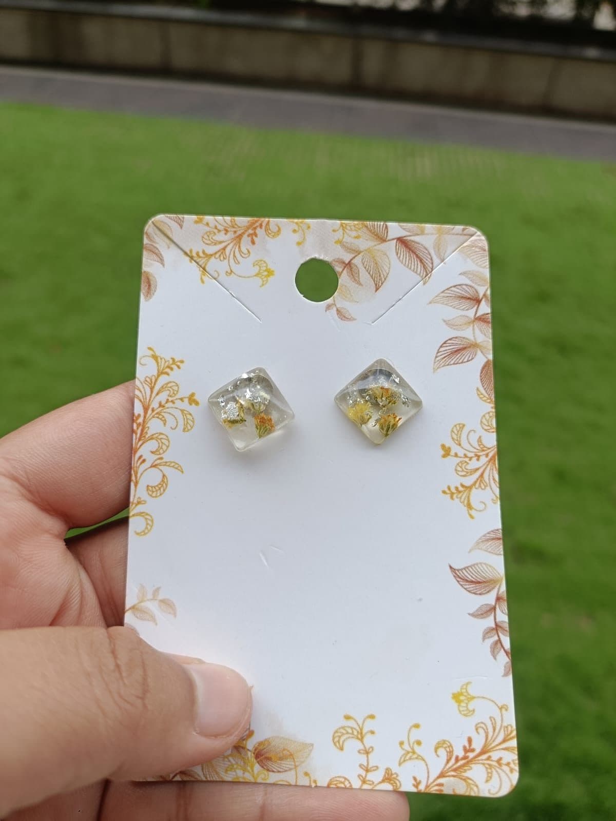 Pearl and floral resin stud earrings on a display card