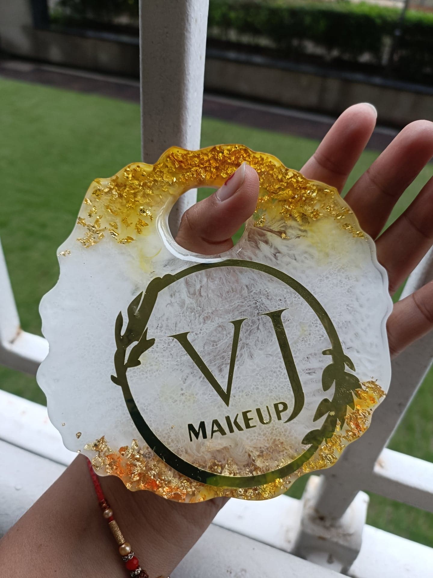 White and gold resin hanging with a custom VJ Makeup logo