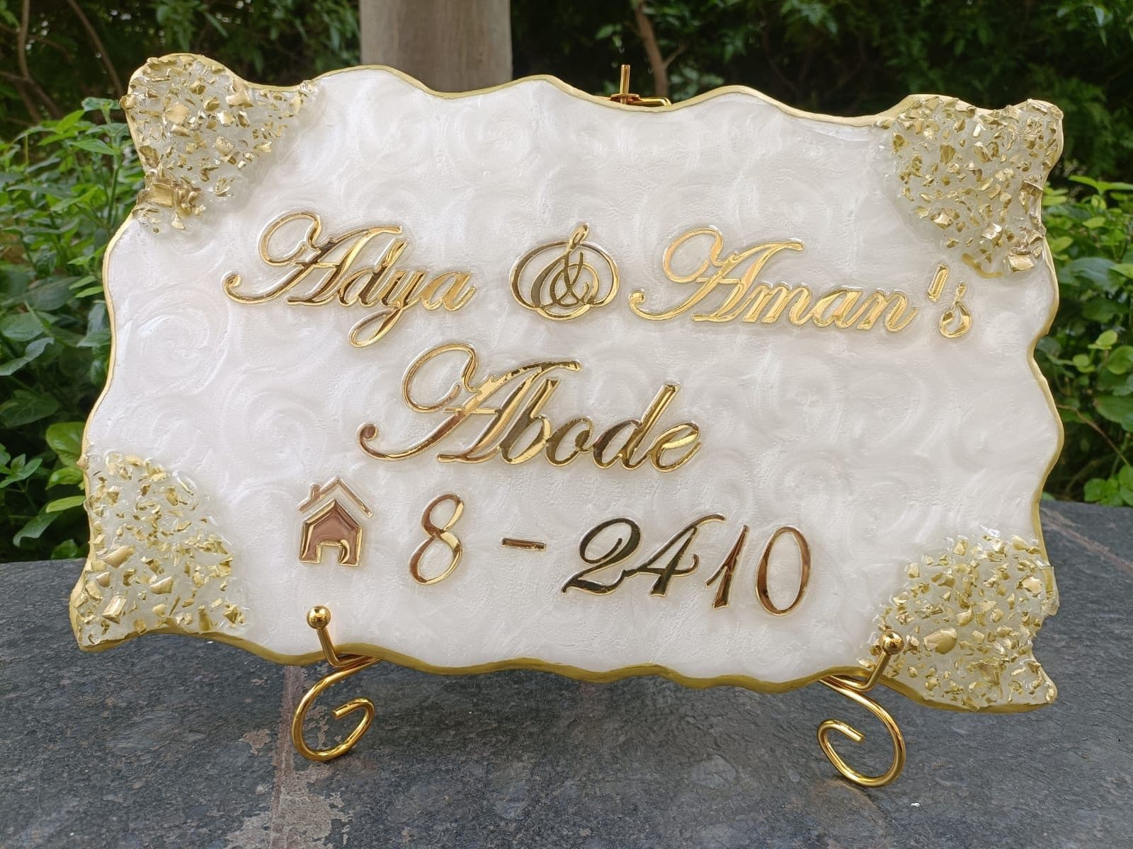 White and gold resin nameplate reading Adya and Aman's Abode, flat 8-2410
