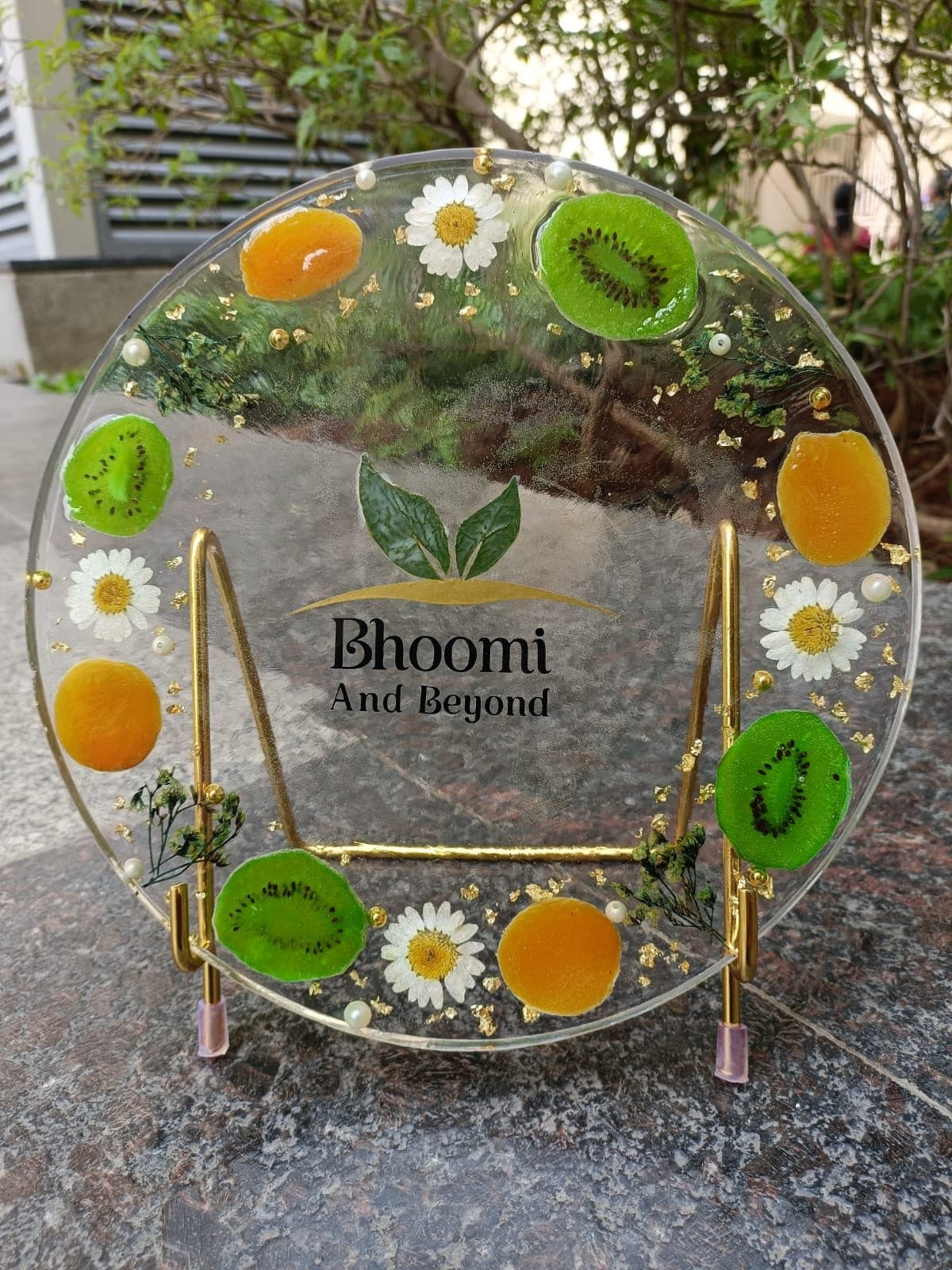 Round resin sign for Bhoomi And Beyond with kiwi, orange slices and daisies